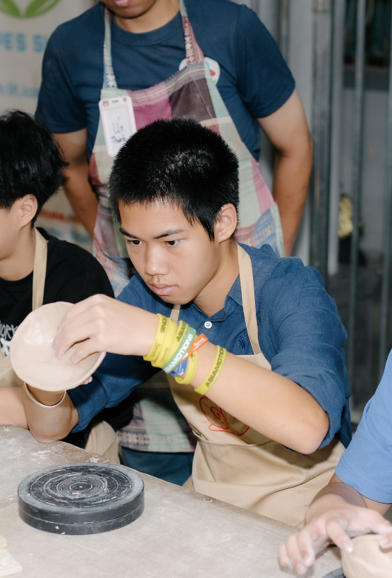 A student shaping clay on a pottery wheel