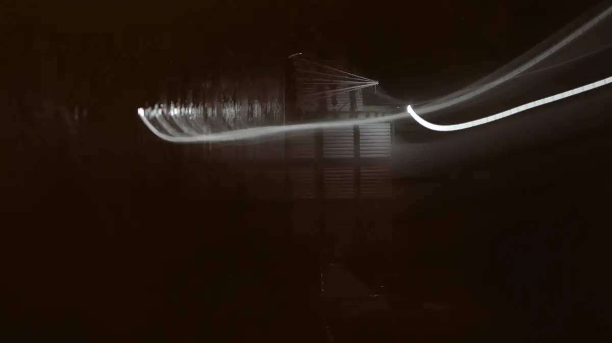 A long white light trail crossing a dark interior