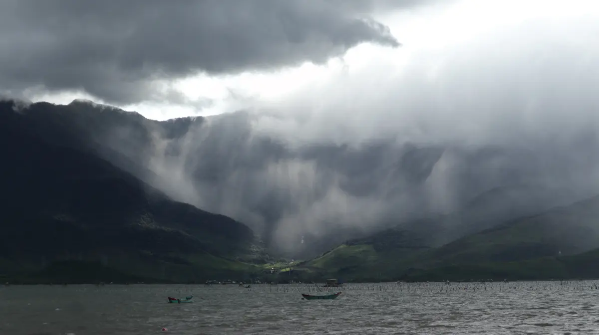 Storm clouds and sun rays above a mountain lake