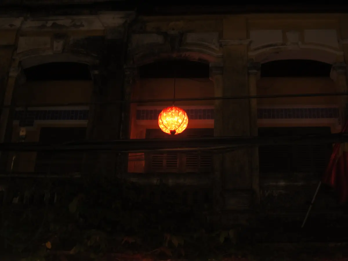 A bright red lantern glowing against a dark building